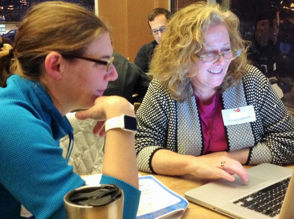 two women smiling looking at a laptop computer